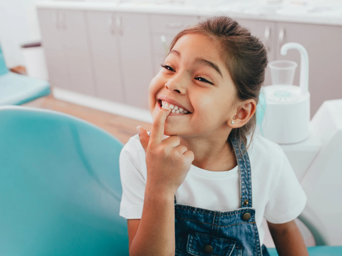Smiling child pointing at teeth in clinic