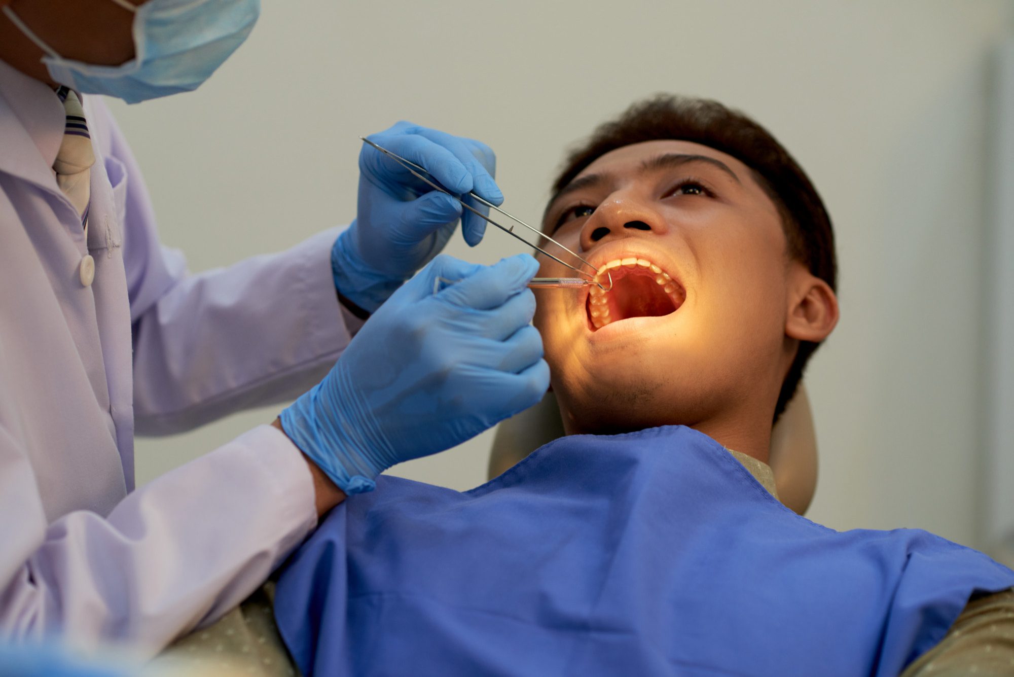 Dentist examining patient's open mouth with tools